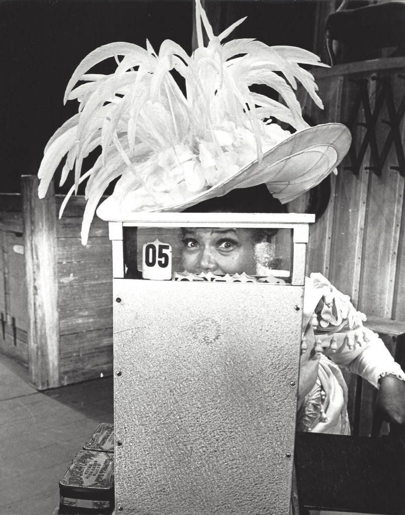 Pearl Bailey in costume, peeking out from behind a cash register.